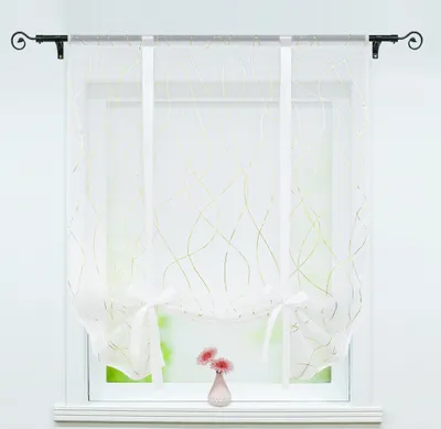 A white sheer curtain with gold wavy lines is hung on a window.