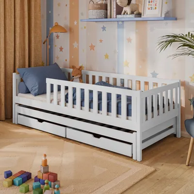A child's bedroom with a white wooden bed, drawers, and toys.