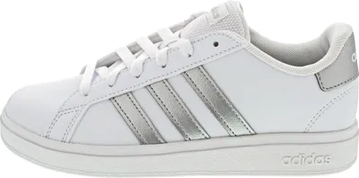 A side view of a white Adidas sneaker with silver stripes.
