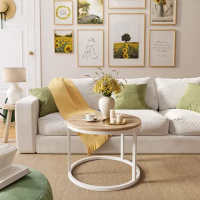 A living room scene with a white sofa, a round coffee table, and framed artwork on the wall.