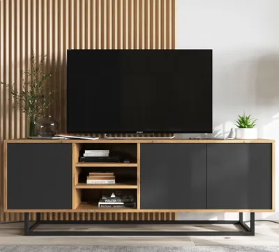 A modern TV cabinet with a television on top, placed in a living room setting with a slatted wood panel wall.