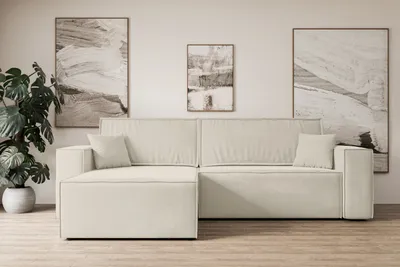 A beige sectional sofa is shown in a living room setting with artwork on the wall and a plant in the corner.