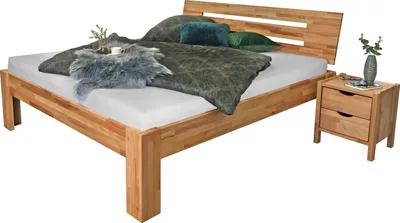 A wooden bed frame with bedding and a nightstand.