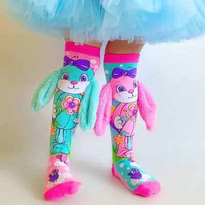 Kind trägt bunte Kniestrümpfe mit großem Hasenmotiv in Pink und Türkis. Die Socken haben flauschige 3D-Ohren und zeigen Blumen-, Vogel- und Wolkenmotive.