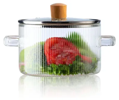 A clear glass pot with a lid, containing vegetables like tomatoes and lettuce.