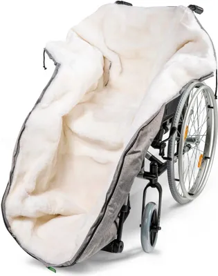 A close-up, angled view of a wheelchair accessory, likely a footmuff or cover, lined with white faux fur and an outer gray fabric, attached to a wheelchair.