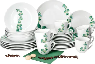 A set of white porcelain dishes and cups with a green eucalyptus leaf pattern, arranged on a white background.
