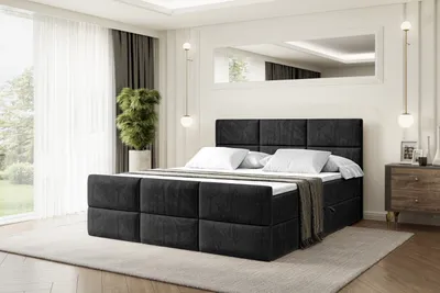 A bedroom scene with a large black upholstered bed as the main focus.