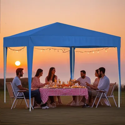People enjoying a meal under a blue canopy at sunset.