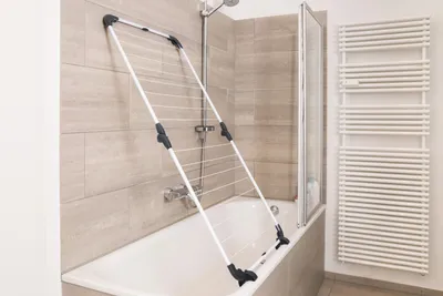 A bathroom with a bathtub, a drying rack, and a towel warmer.