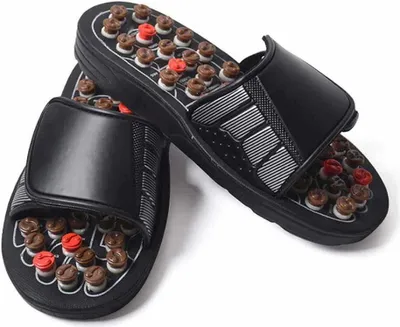 A pair of black acupressure flip-flops with brown and red massage nodes on the soles.
