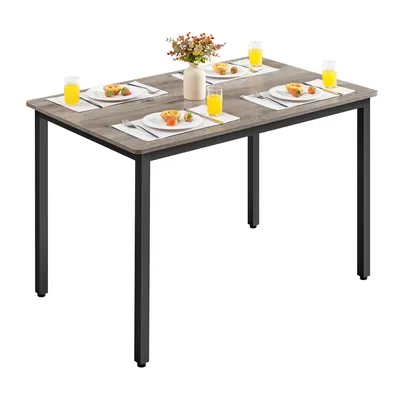 A dining table set for four people with placemats, plates, and glasses of orange juice.