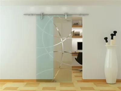 A modern glass sliding door with a frosted geometric pattern, installed in a room with a desk and computer visible through the open door.