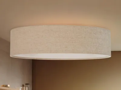 A close-up shot of a round LED ceiling light with a linen fabric shade, mounted on a beige ceiling.