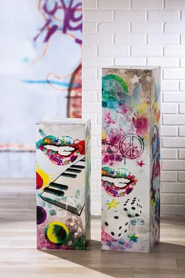 Two decorative pedestals with graffiti-style art are shown in a room with a brick wall.