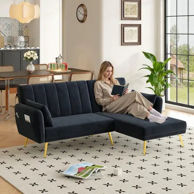 A woman reads a book on a black sectional sofa with gold legs in a living room.