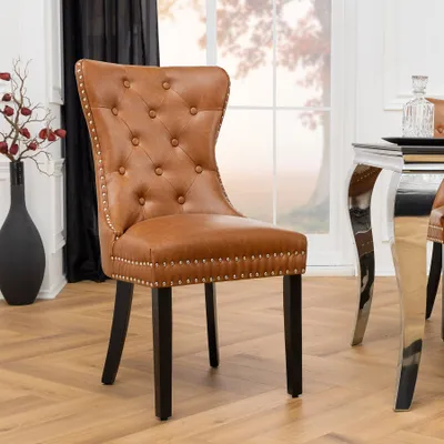 A brown tufted dining chair with silver nailhead trim and dark wooden legs is shown in a dining room setting.