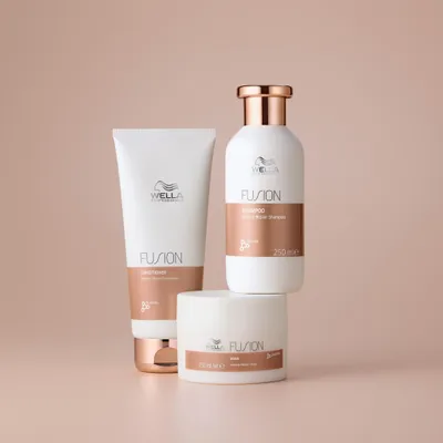 Three Wella Fusion hair care products arranged on a light pink background.