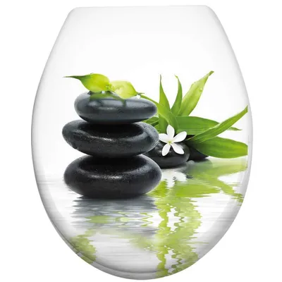 A stack of black stones with green bamboo leaves and a white flower, reflected in water.