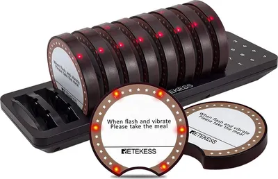 A set of restaurant pagers and their charging base, with two individual pagers in the foreground.