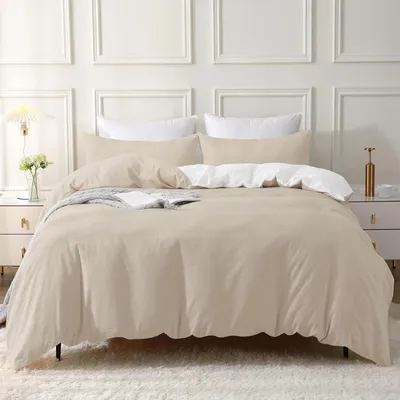 A neatly made bed with beige bedding and white pillows in a room with decorative wall paneling.