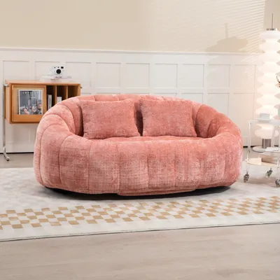 A plush pink loveseat sits on a checkered rug in a well-lit room.