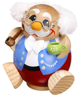 Ein hölzerner Räuchermann in Form eines fröhlichen Opas mit weißem Haar und Brille hält eine Pfeife und eine grüne Tasse während er in einem blauen Hemd und roten Hosen sitzt