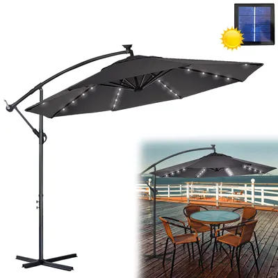 A dark gray cantilever umbrella with LED lights and a solar panel, shown against a white background. A smaller inset image shows the umbrella set up over a table and chairs on a wooden deck.