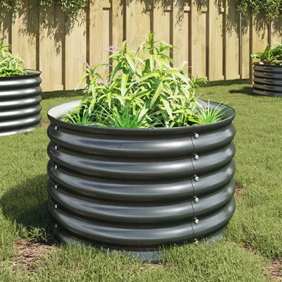 Raised garden beds filled with plants in a grassy yard with a wooden fence.