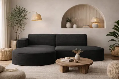A modern living room with a dark fabric sectional sofa, a round wooden coffee table, and decorative elements.