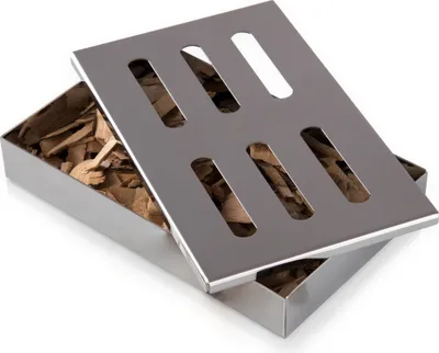 A stainless steel smoker box filled with wood chips, with its lid slightly ajar.