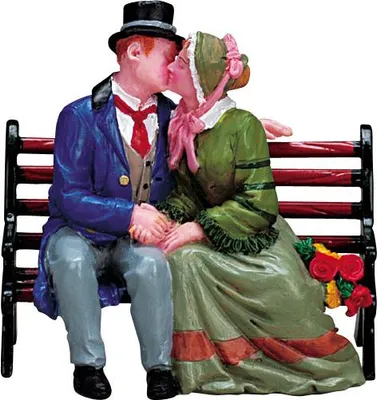 A figurine of a couple kissing on a park bench.