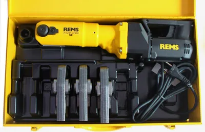 A yellow and black REMS press machine with accessories is neatly arranged in a black insert within a yellow case.