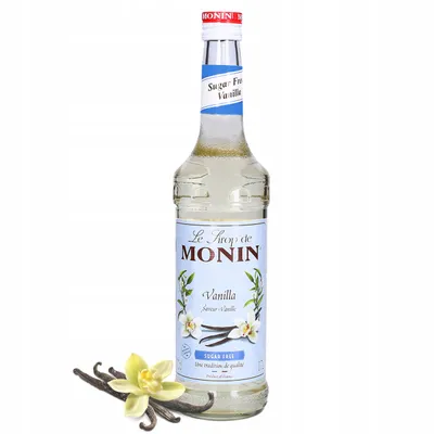 A bottle of Monin Vanilla syrup with vanilla beans and a flower.