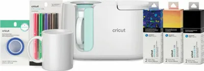 A collection of Cricut crafting supplies, including a mug press, mug, markers, tape, and sublimation ink cartridges, arranged on a white background.