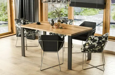 A dining table with chairs in a modern dining room setting with large windows overlooking a garden.