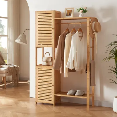 A wooden wardrobe stand with clothes hanging on it, a hat and scarf on the side, and a handbag on a shelf. The background shows a room with a window and a lamp.
