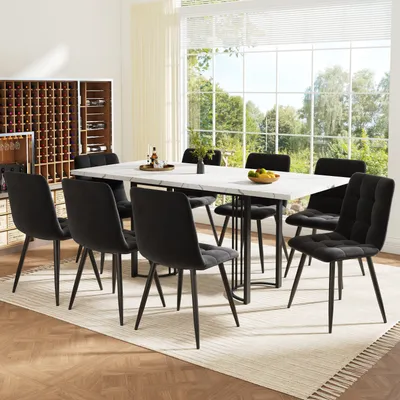 A dining set with a marble-top table and black velvet chairs in a well-lit room with a large window overlooking a garden.