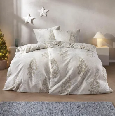 A bedroom scene with a bed dressed in festive bedding, decorated with Christmas stars and a small Christmas tree.
