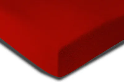 A close-up, angled view of a red fabric product, likely a bed sheet, with a soft texture and a shadow cast on the white background.