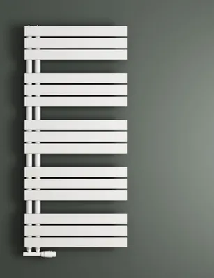 A white radiator is mounted on a gray wall.
