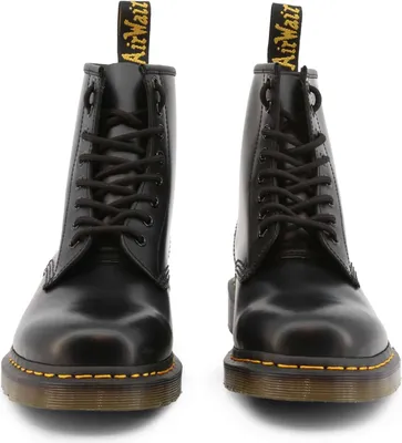 A pair of black Dr. Martens boots are shown from the front against a white background.