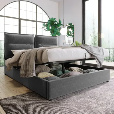 A modern bedroom with a grey upholstered bed frame featuring a lifted mattress to reveal storage underneath, filled with pillows.
