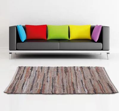 A modern living room scene with a black sofa and colorful pillows, and a rug in front of it.