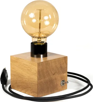 A close-up studio shot of a wooden cube desk lamp with a large Edison bulb.