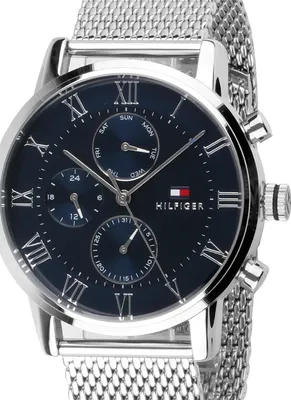 A close-up, studio shot of a Tommy Hilfiger watch with a blue face and silver mesh band.