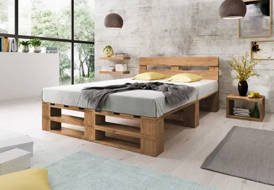 A bedroom with a wooden pallet bed, pillows, and a blanket.