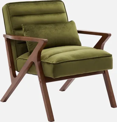 A green velvet armchair with wooden legs and a small pillow.