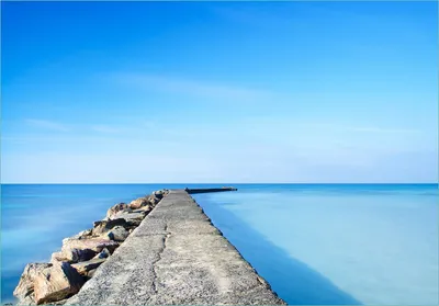 Produktbild von Wallario Fototapete Vliestapete, seidenmatte Oberfläche, einfache Verarbeitung, Größe 300 x 210 cm, Motiv Pier am blauen Ozean mit blauem Himmel
