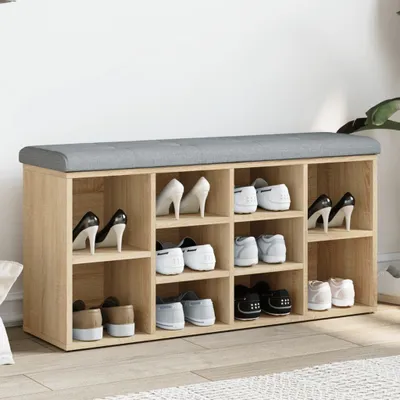 A shoe bench with multiple compartments, some filled with shoes, against a white wall.